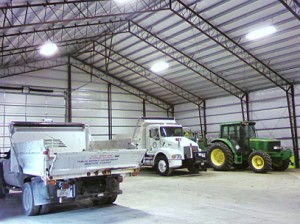 The inside of a metal building with two trucks and a tractor inside