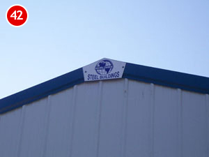 A triangular sign atop the steel building reads "Steel Buildings," a testament to expert steel building construction. Against the backdrop of a clear blue sky, a small red circle with the number 42 graces the top left corner.