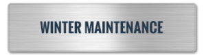 A metallic sign with a brushed texture is mounted on the steel building, displaying the words "WINTER MAINTENANCE" in bold, dark lettering.