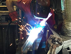 A closeup shot of a Worldwide Steel Buildings' employee welding steel to make trusses for a steel building kit.