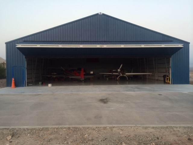 A dark blue, steel airplane hangar built by Worldwide Steel Buildings for a client in Chile.