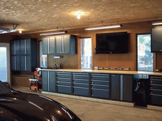 A tool bench with a lot of storage and a mounted tv inside of a metal garage
