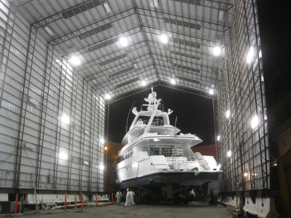 A white yacht inside of an outdoor steel building.
