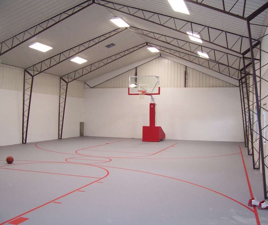 An indoor basketball court inside of a metal building constructed by Worldwide Steel Buildings