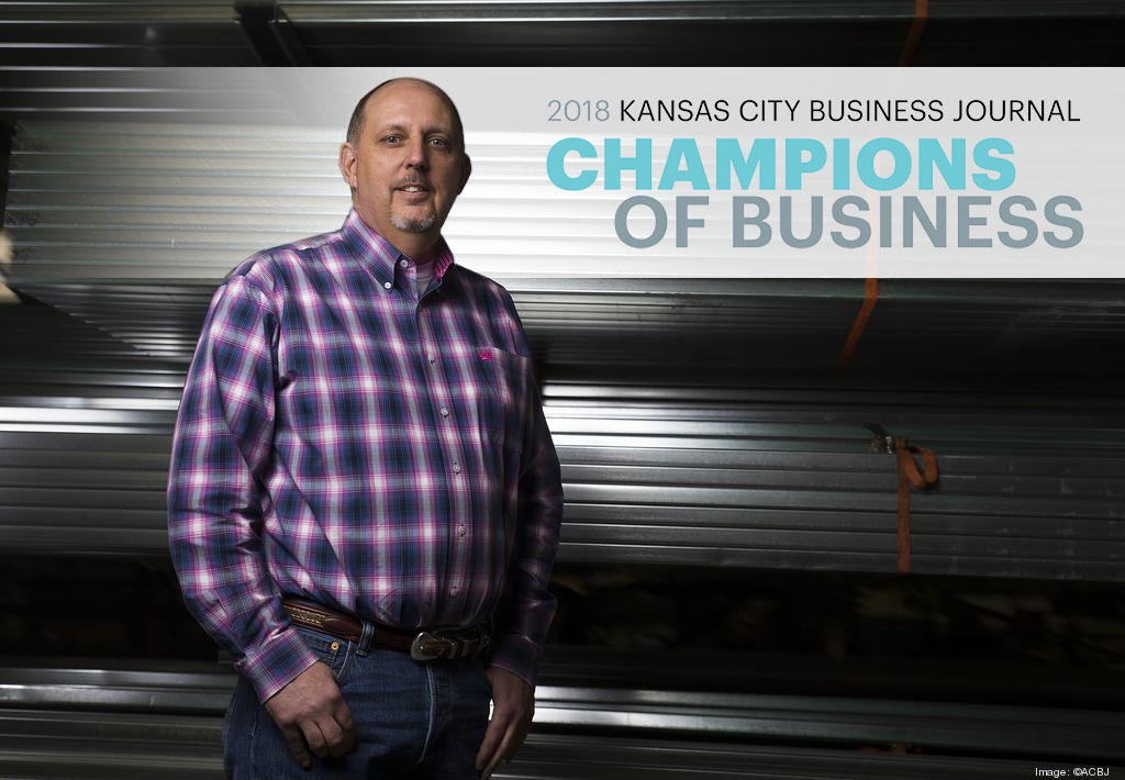 A man in a plaid shirt stands proudly in front of metallic structures, embodying the spirit of championing customers' goals. The text above celebrates the "Kansas City Business Journal Champions of Business 2018.