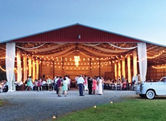 An outdoor metal building wedding venue with a wedding reception taking place