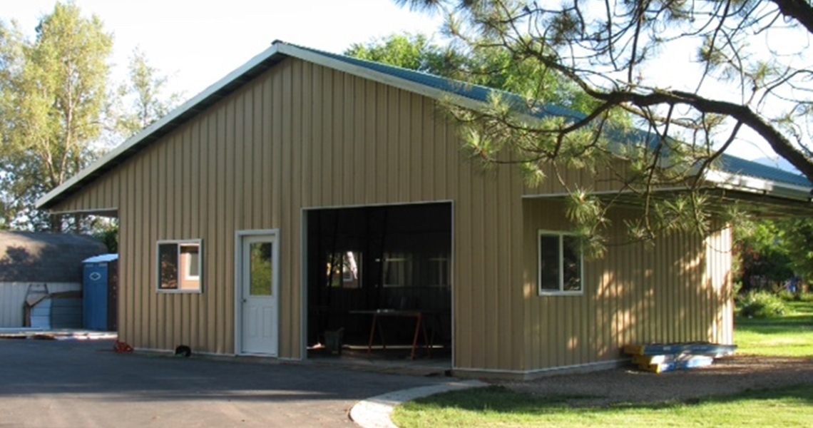 View from the front of a custom metal garage with overhang built by Worldwide Steel Buildings.