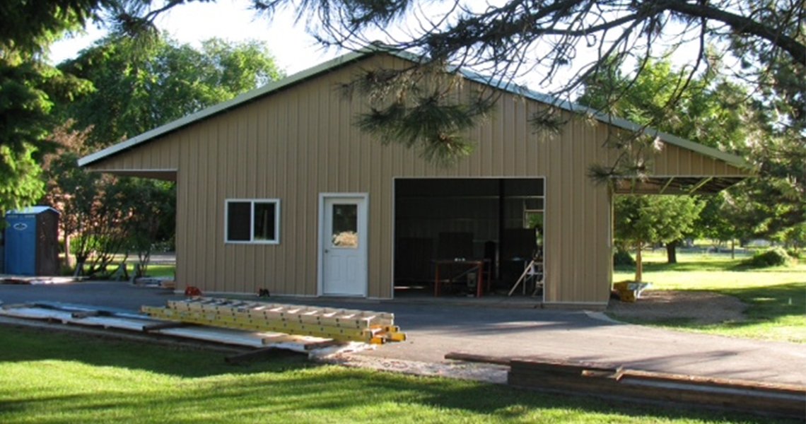 View from the front of a custom metal garage with overhang built by Worldwide Steel Buildings.