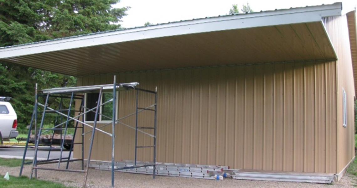 Side of a custom metal garage with overhang designed and built by Worldwide Steel Buildings.