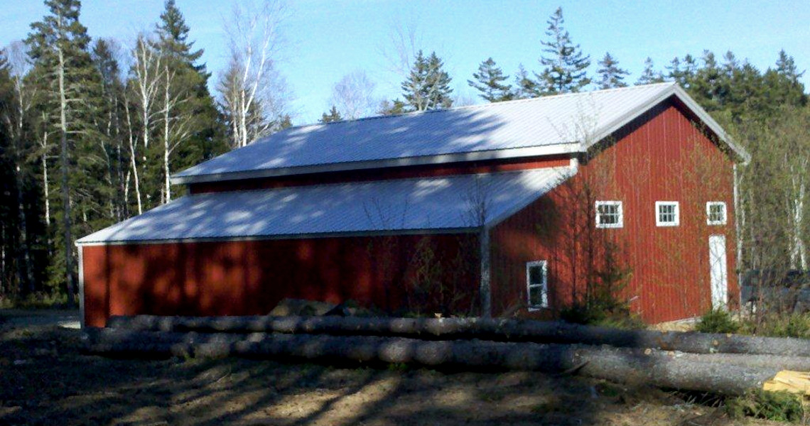 The side of a red building with a half truss roof that was designed and built by Worldwide Steel Buildings.