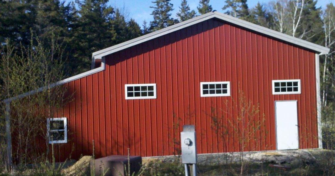 The back of a red building with a half truss roof that was designed and built by Worldwide Steel Buildings.