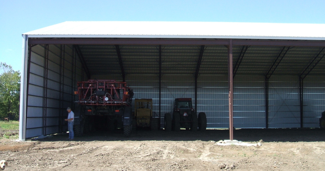 An equipment storage building designed and built by Worldwide Steel Buildings with two tractors inside.