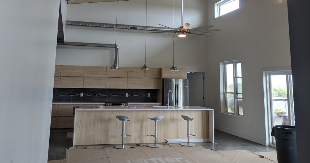 Modern kitchen with light wood cabinets and high ceilings in barndominium.
