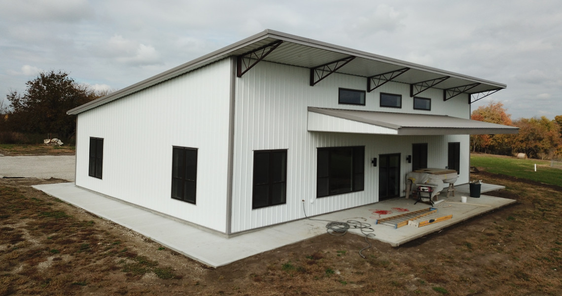 An exterior shot of the back of a metal barndominium designed and built by Worldwide Steel Buildings featuring a single slope roof.