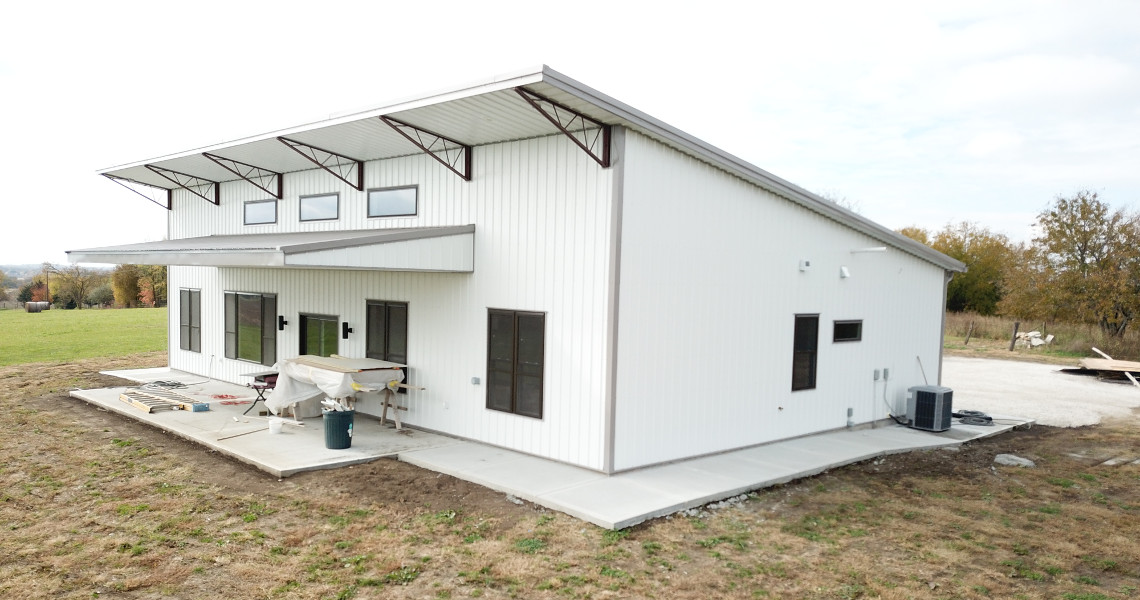 An exterior shot of the back of a metal barndominium designed and built by Worldwide Steel Buildings featuring a single slope roof.