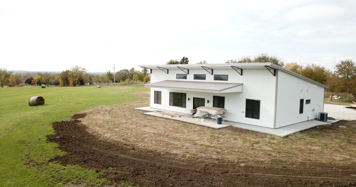 An exterior shot of the back of a metal barndominium designed and built by Worldwide Steel Buildings featuring a single slope roof.