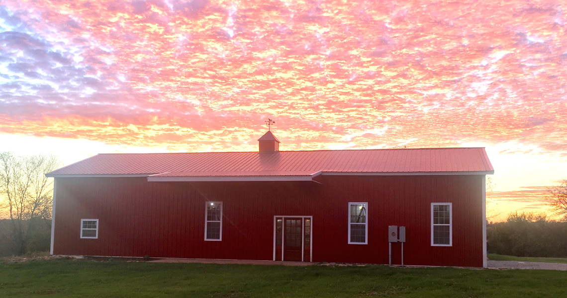 A metal building with a red exterior against a sunset
