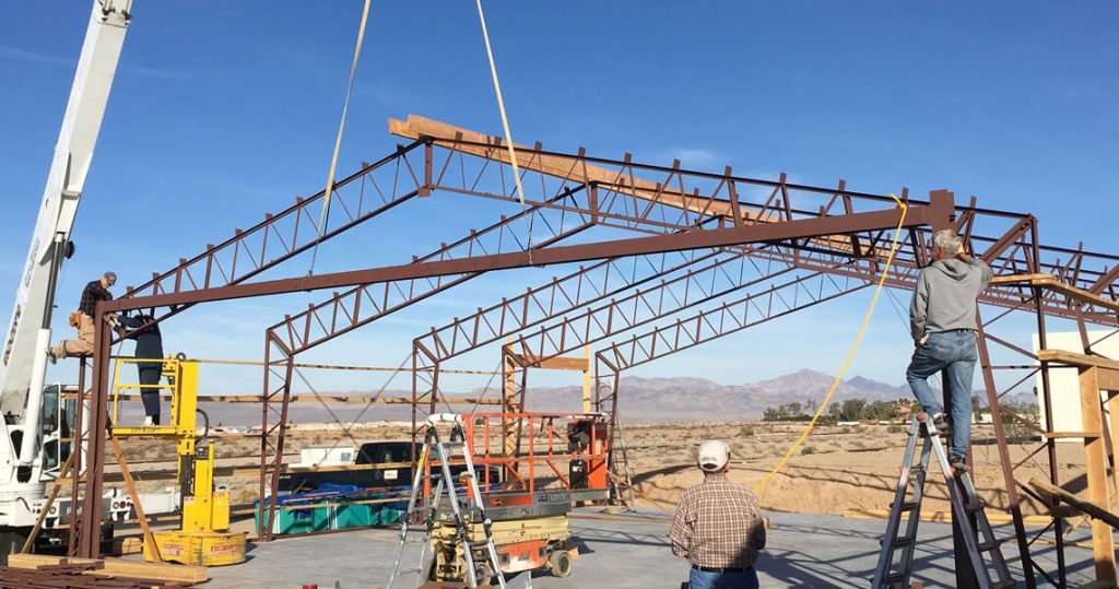 Construction workers building a metal frame for an airplane hangar.
