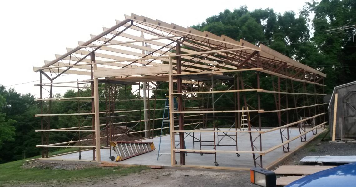A wooden frame and beginning stages of a hybrid building by Worldwide Steel Buildings.