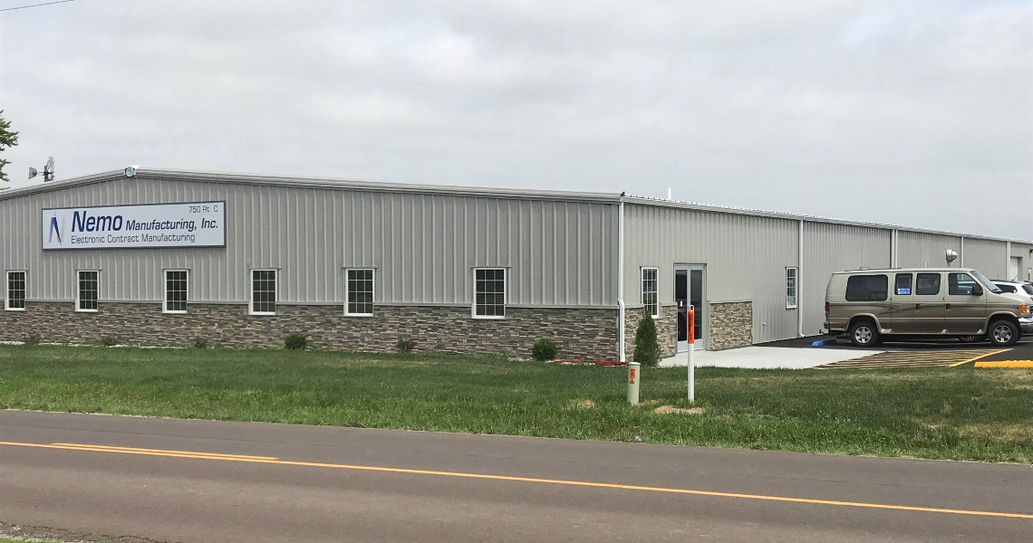 A large, single-story industrial building features a sign that reads 