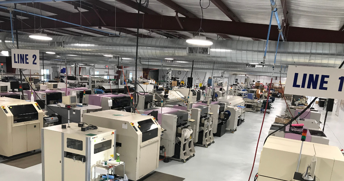The expansive Mfg facility boasts multiple assembly lines humming with precision. Signs labeled 