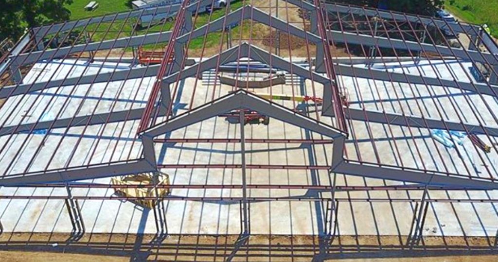 A metal building currently under construction with the just the frame completed.