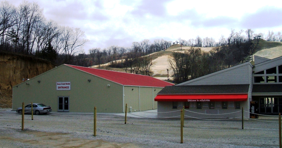 At Snow Creek Ski Resort, the entrance boasts two buildings with distinctive red roofs. The main building displays a sign reading 