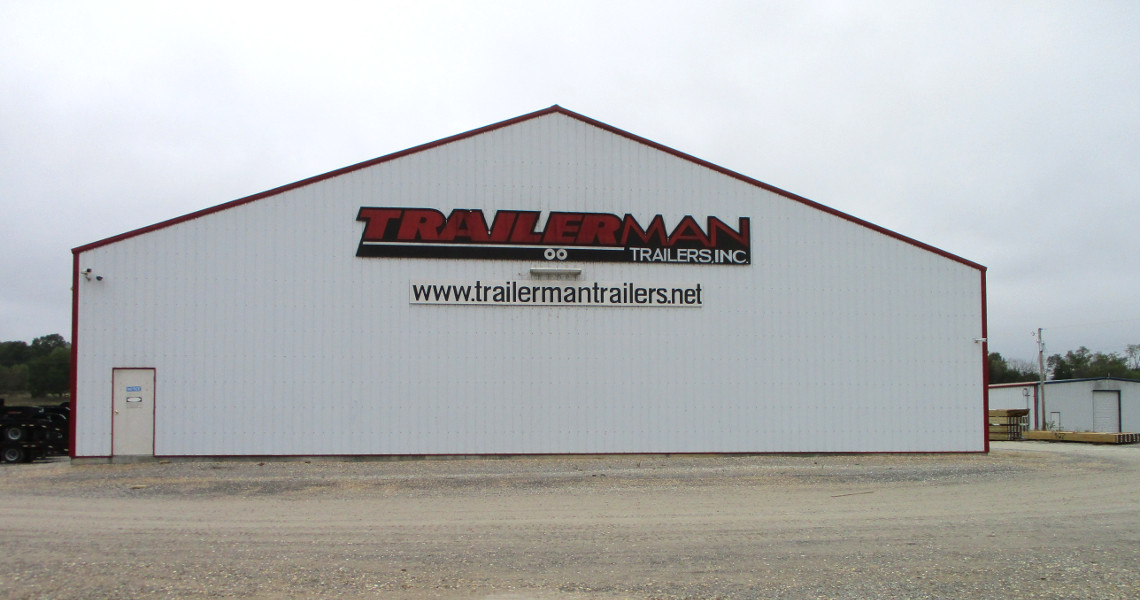 A large white building with a sloped roof proudly displays a sign that reads 