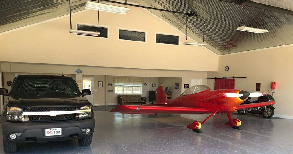 Interior of metal garage with truck, airplane and motorcycle.
