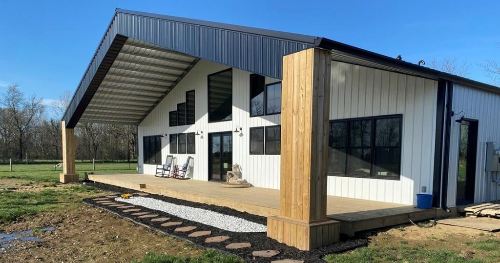 White barndominium with black accents and large porch.
