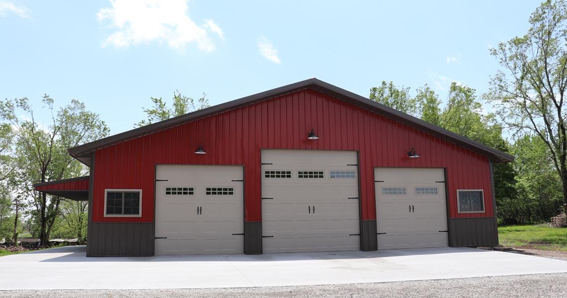
A metal garage building with three doors and a brick red exterior