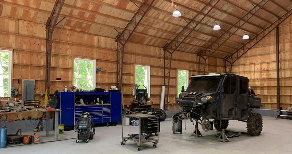 Interior of large garage space with a vehicle being worked on in the center.
