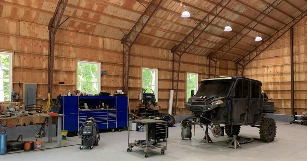 Interior of large garage space with a vehicle being worked on in the center.