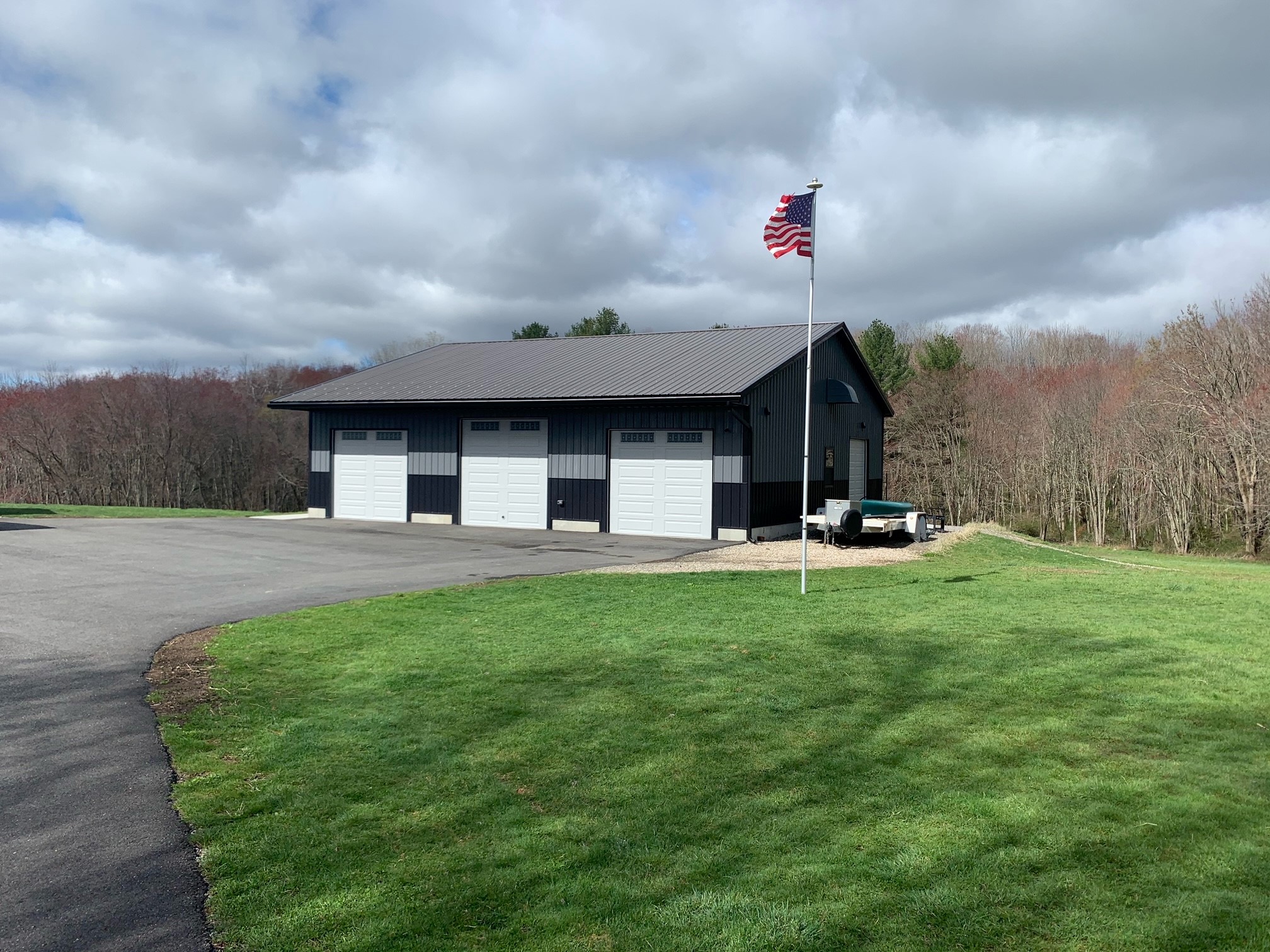 A white and gray outdoor, steel workshop built in Watertown, CT by Worldwide Steel Buildings.