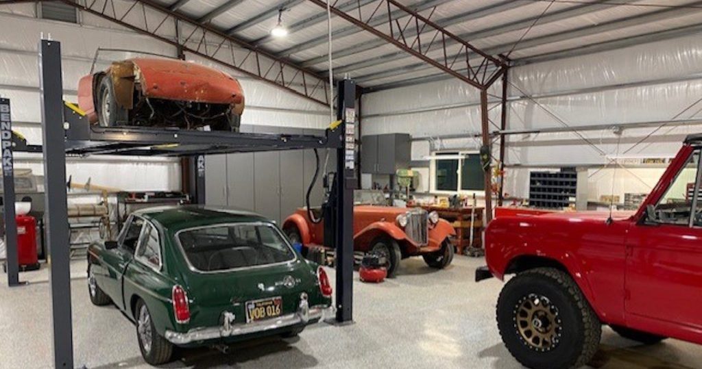 Interior of metal garage with hobbyist vehicles.