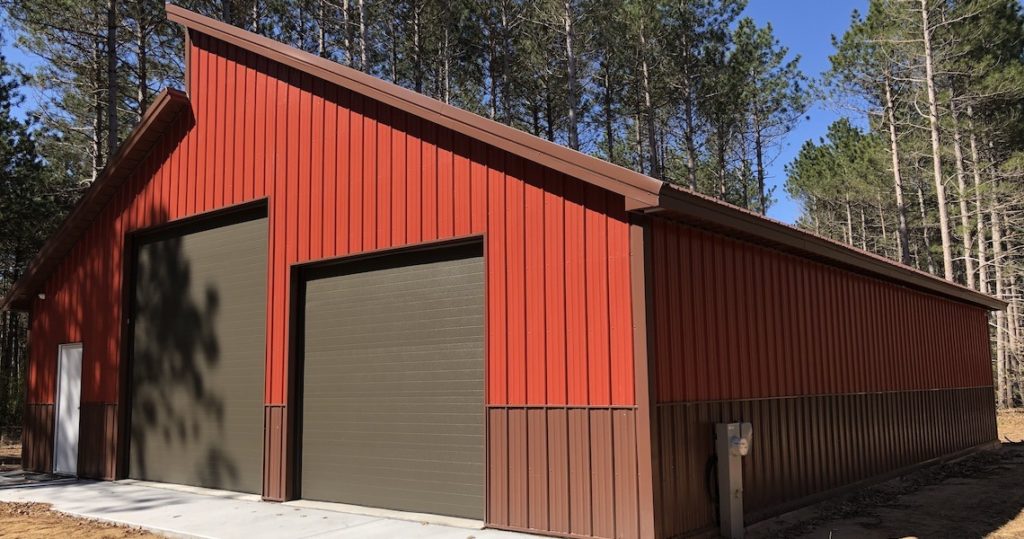 A metal garage building with a brick red exterior
