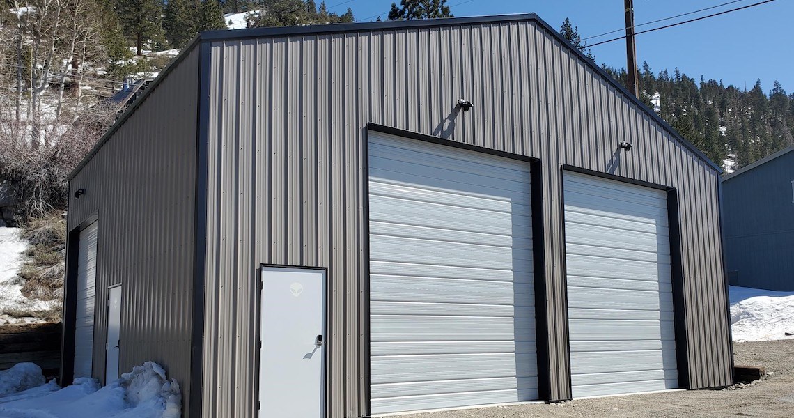 A light gray steel garage built in June Lake, CA by Worldwide Steel Buildings.