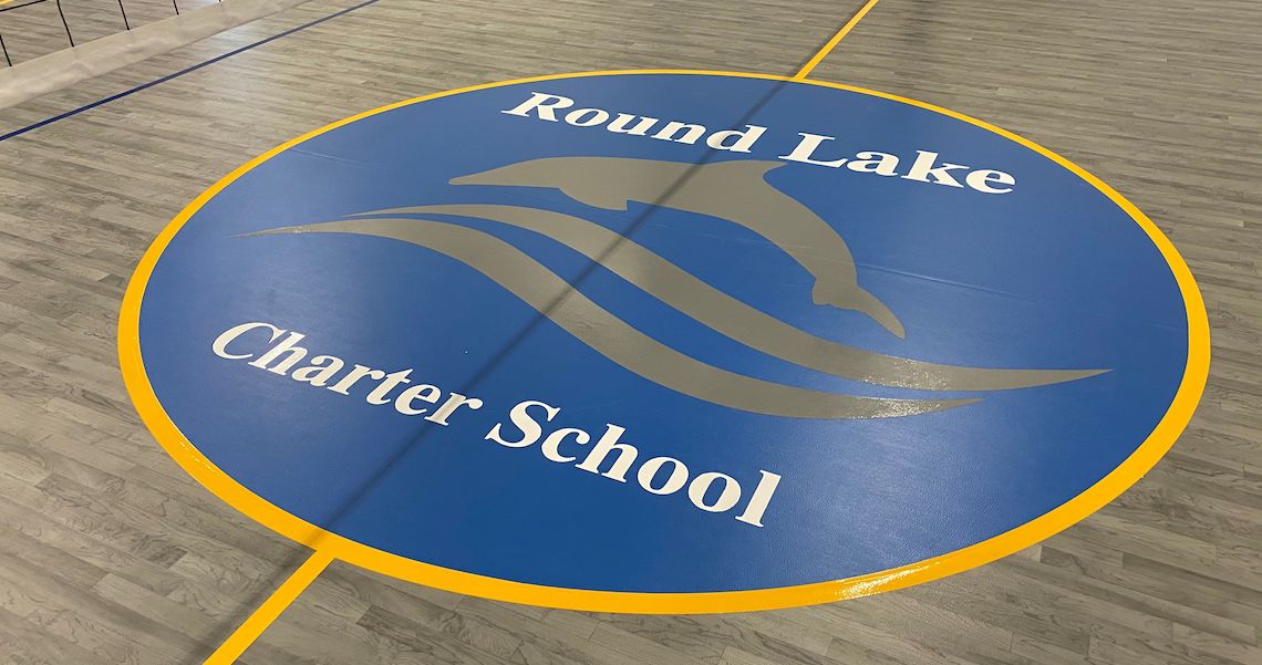 A gym floor boasts a striking logo with a large blue circle at its heart. It proudly displays 
