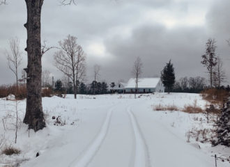 Steel home in winter, at the end of a long snow-covered driveway