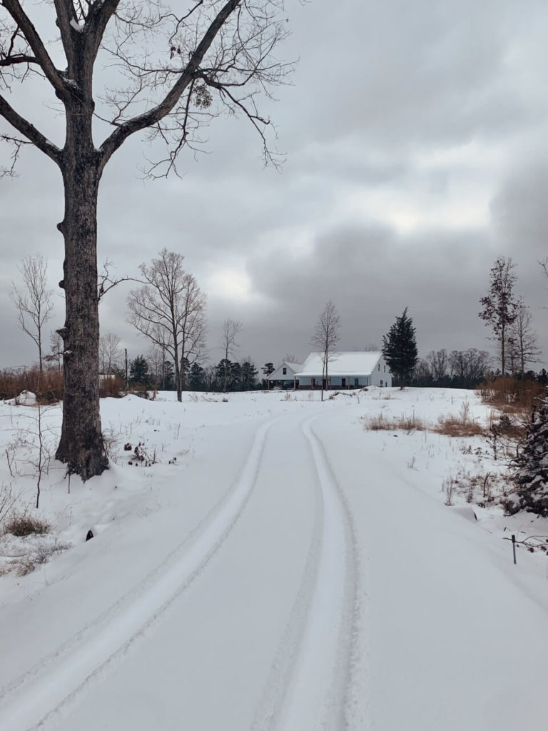 Steel home in winter, at the end of a long snow-covered driveway