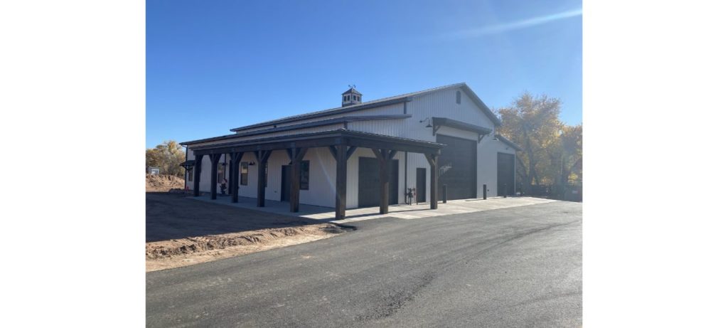 White barndominium with black garage doors.