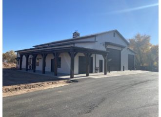 White barndominium with black garage doors.