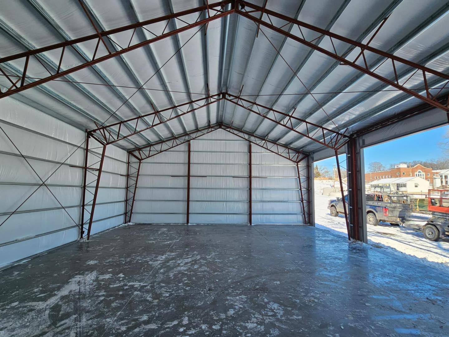 Sunlit, empty warehouse with open door showing snowy vehicles and houses, evoking a serene sanctuary.