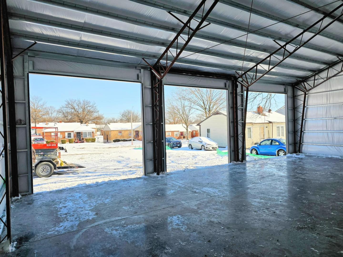 Garage interior with concrete floor, doors open to snowy neighborhood and Second Baptist Church steeple.
