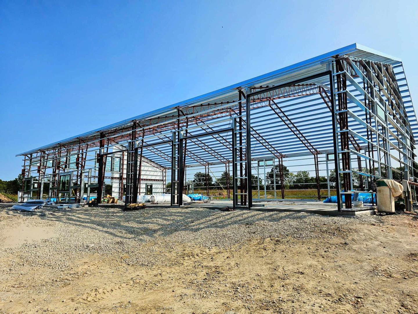 Metal framework on a construction site under a blue sky, with exposed beams and scattered materials.