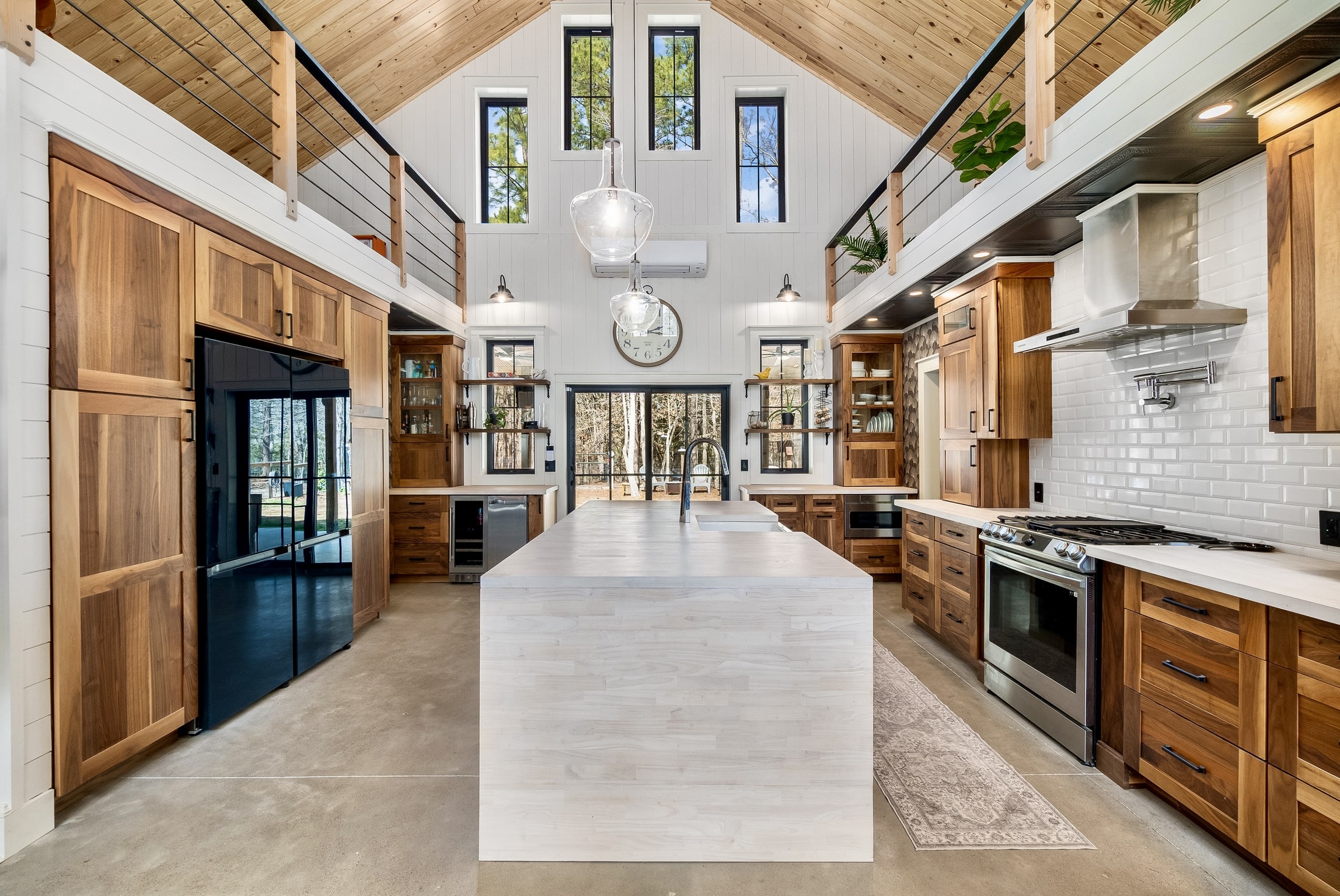 Modern kitchen with vaulted wood ceiling, island, wood cabinets, and tall windows for natural light.