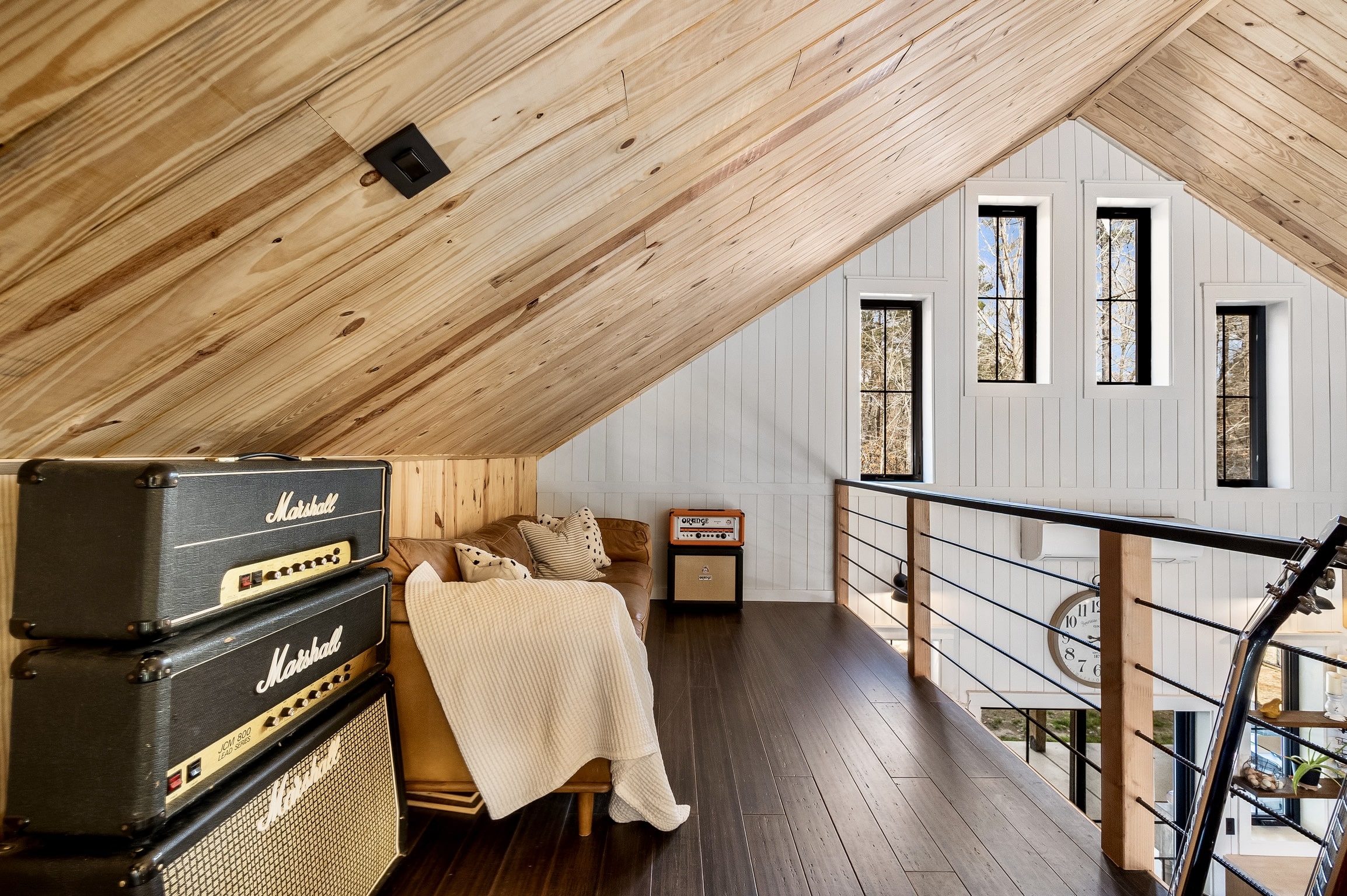 Cozy loft with wood walls, couch, guitar, amps, and window view of Shipyard Creek.
