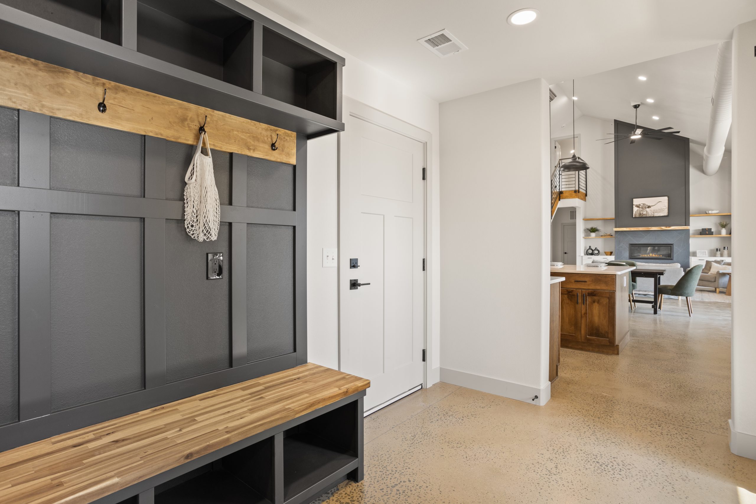 Bench with storage cubbies and wall hooks next to a living room entryway inside a barndominium in Cheyenne, Wyoming