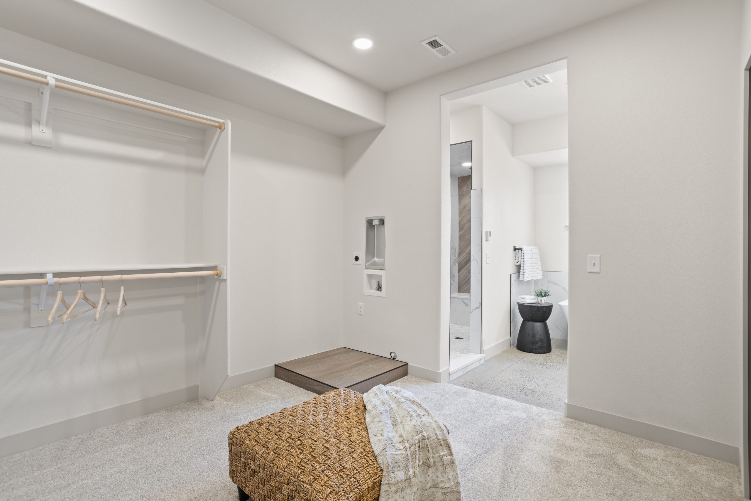 Closet rods and ottoman inside a bedroom connecting to a bathroom in Cheyenne, Wyoming