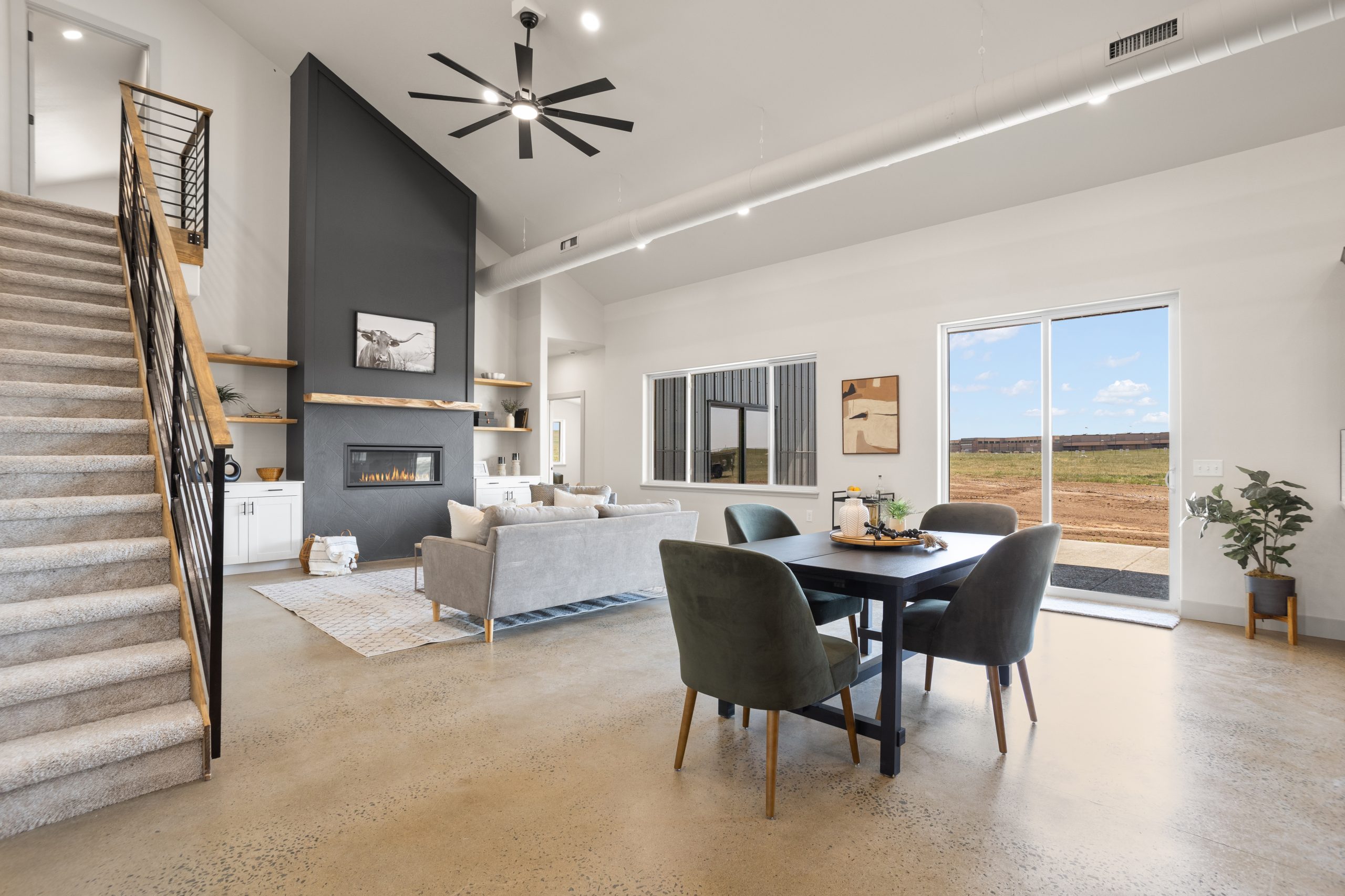 Living room with a staircase, fireplace and a window door inside a barndominium in Cheyenne, Wyoming